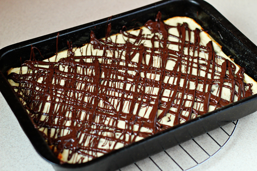 chocolate chunk cheesecake bars recipe with step by step pictures, stir the melted chocolate until smooth, then drizzle the chocolate over the cheesecake