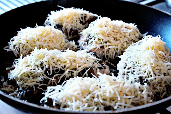 chicken with mushrooms and cheese step by step recipe with ingredients and pictures, chicken fillets covered with mushroom sauce and shredded cheese in a large frying pan, skillet
