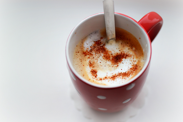 cappuccino in a red mug with polka dots with cinnamon heart on top