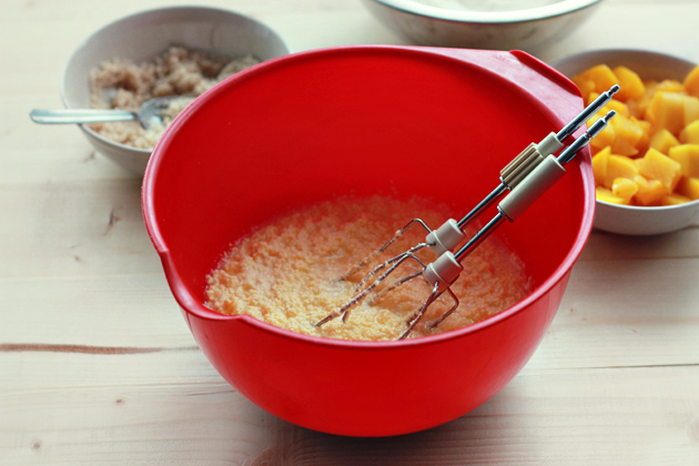 wet ingredients in a whisking bowl with wisks for peach and cinnamon cobbler muffins